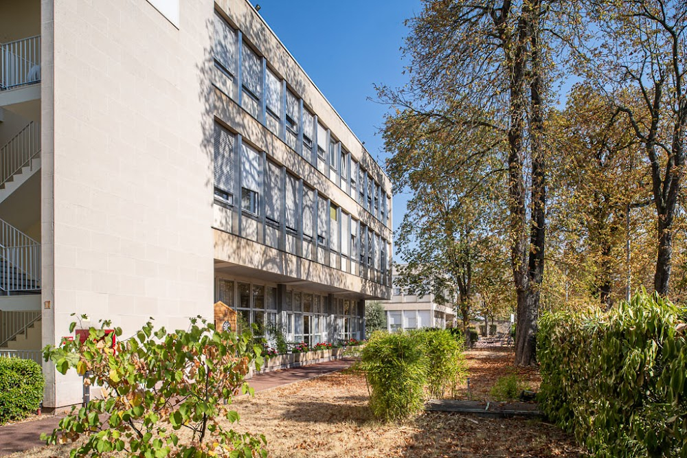 Les espions : a person walks along a high wall to the entrance gate of a clinic