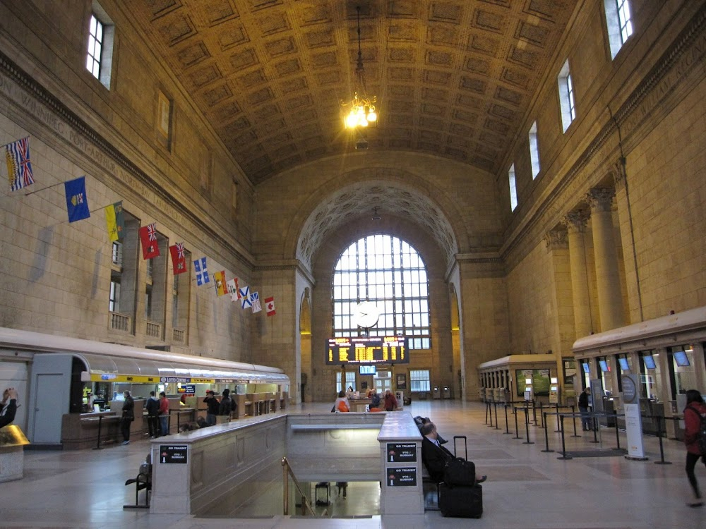 The Last Chase : Exterior - Franklyn walks by building columns and newsstand